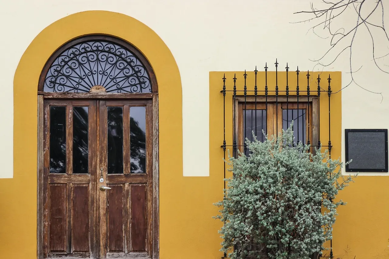 Arched hardwood front door and timber window frame on a house