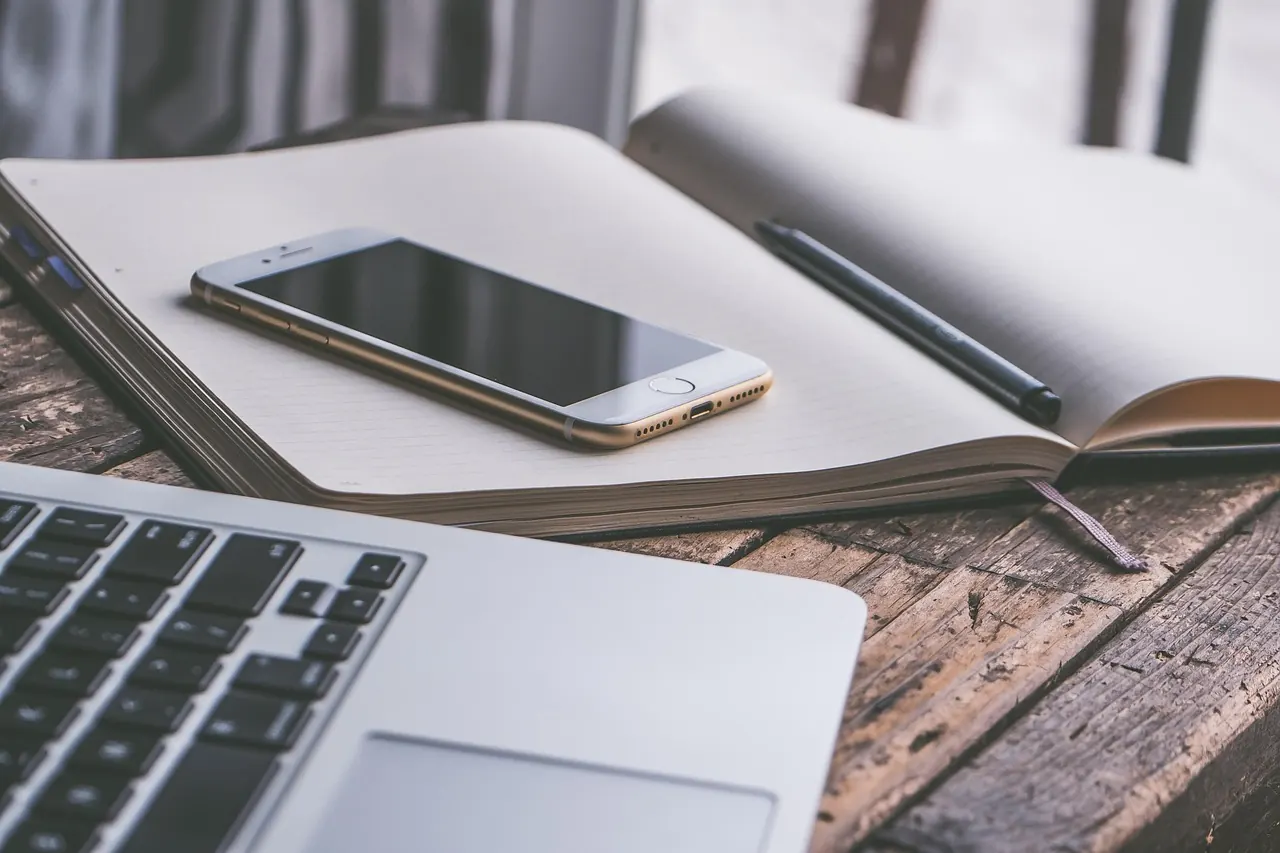 Notebook, phone and laptop on a desk