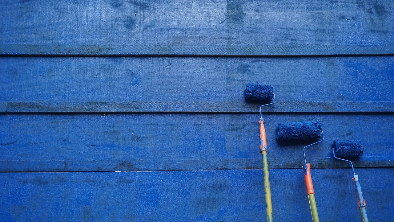 Paint rollers on a freshly painted blue wall