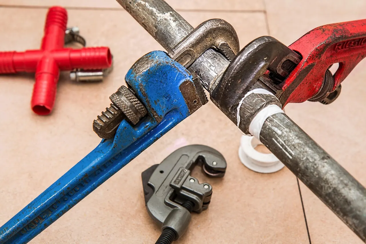 Plumbing pipe wrenches and pipe cutter on a water pipe