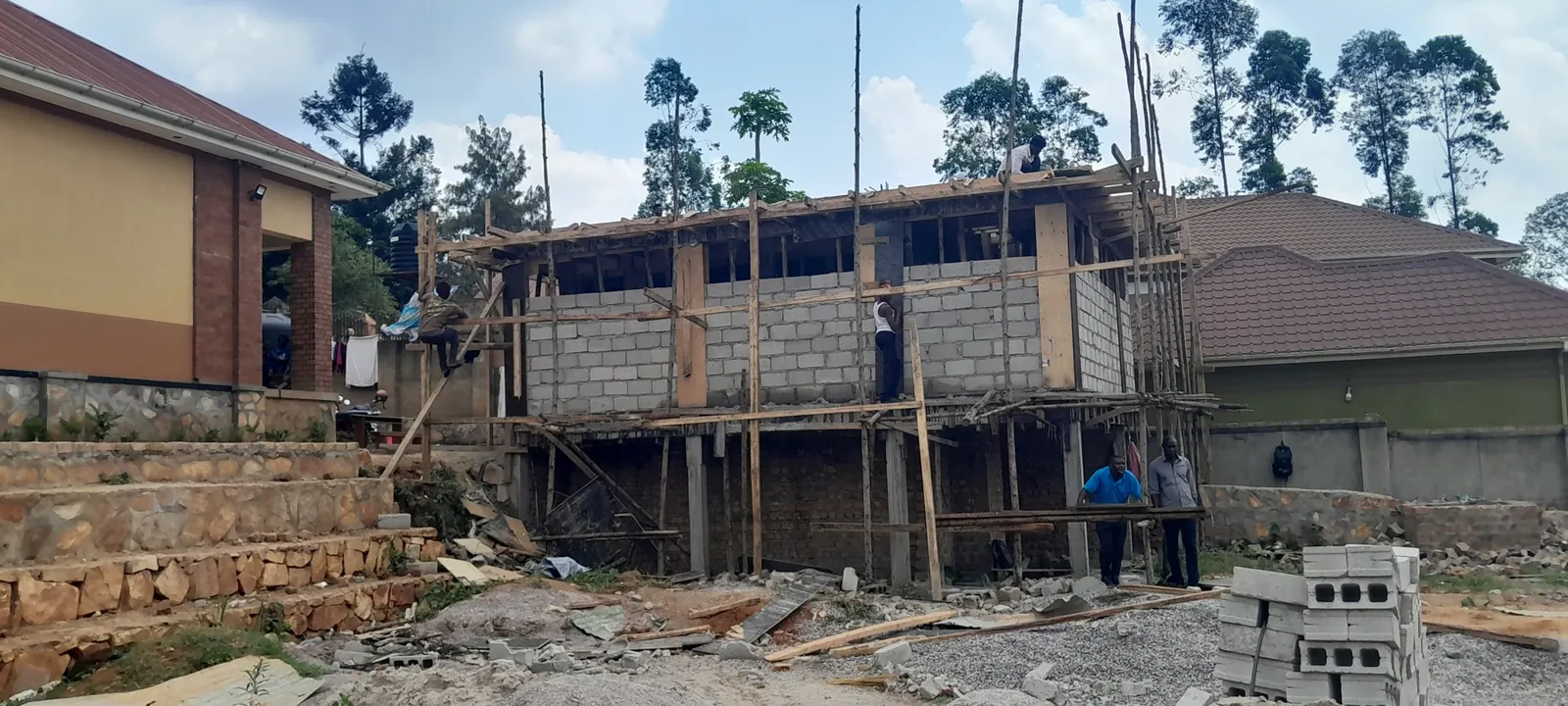 Residential house under construction with block walls and timber scaffolding in Uganda