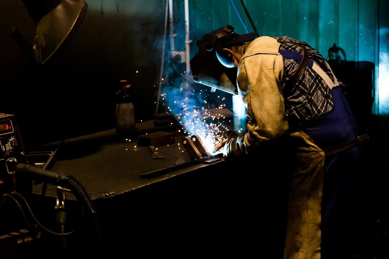 Welder in full protective gear fabricating steel in a workshop
